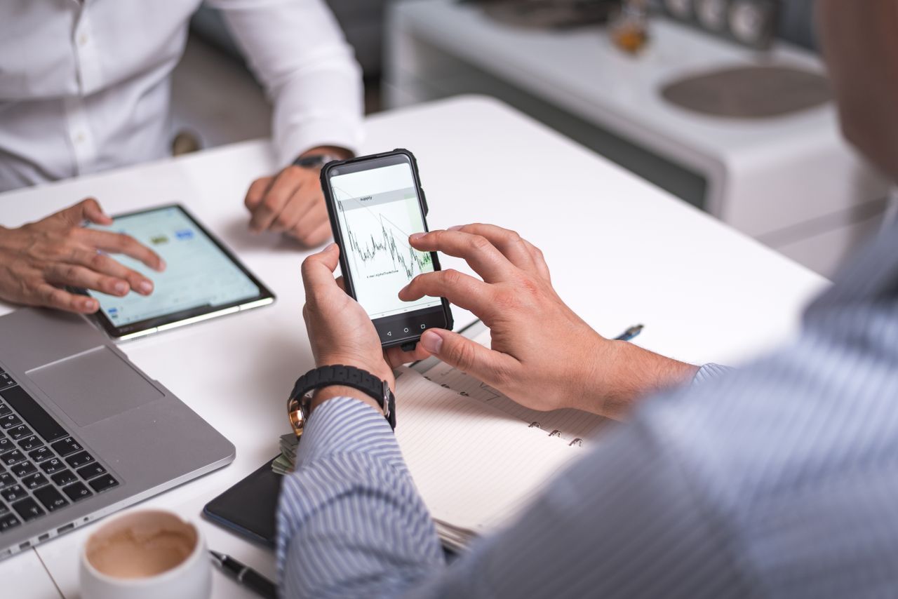 Business professionals collaborating with smartphones and tablets analyzing digital charts.